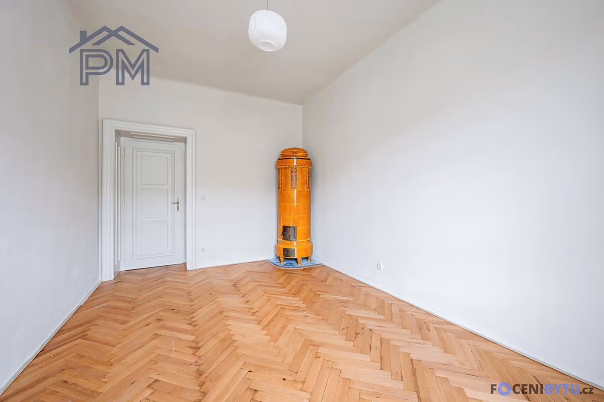 Nezařízený pokoj s kachlovými kamny v rohu