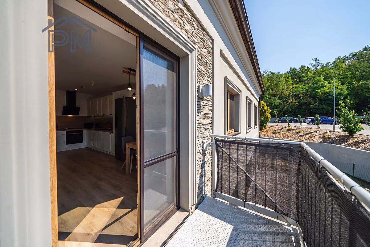 Balkon se sítí proti slunci a otevřenými dveřmi do kuchyně