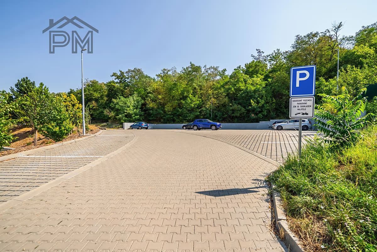 Vydlážděné parkoviště u domu s cedulí vyhrazující parkování obyvatelům