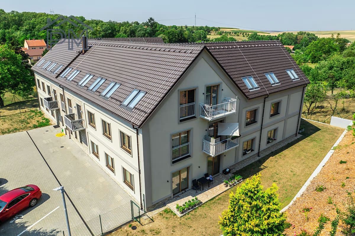 Letecký pohled na dům se sedmnácti byty, balkony a střešními okny