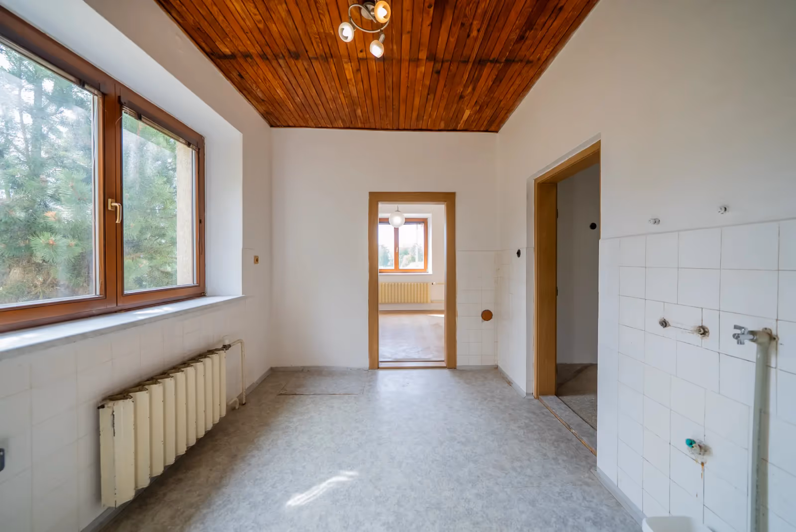 Druhý pohled do kuchyně — přípojky na stěně a průhled do pokoje