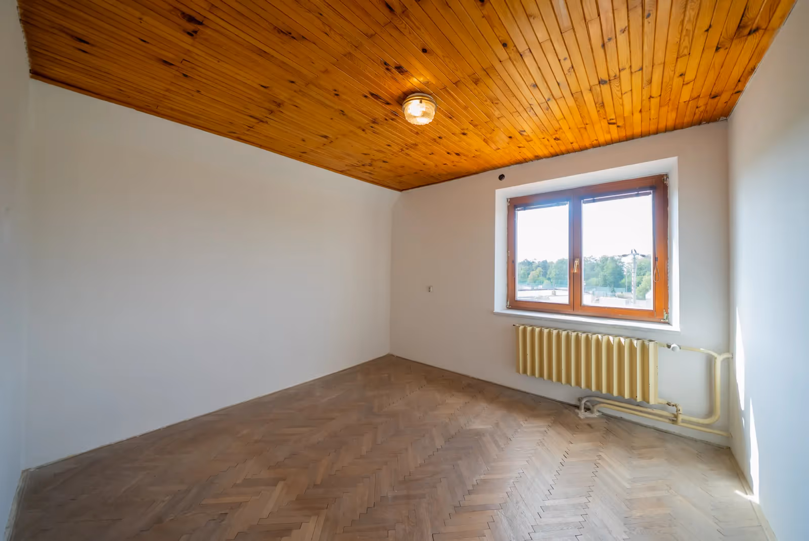 Pokoj v patře s výhledem přes střechy na zeleň
