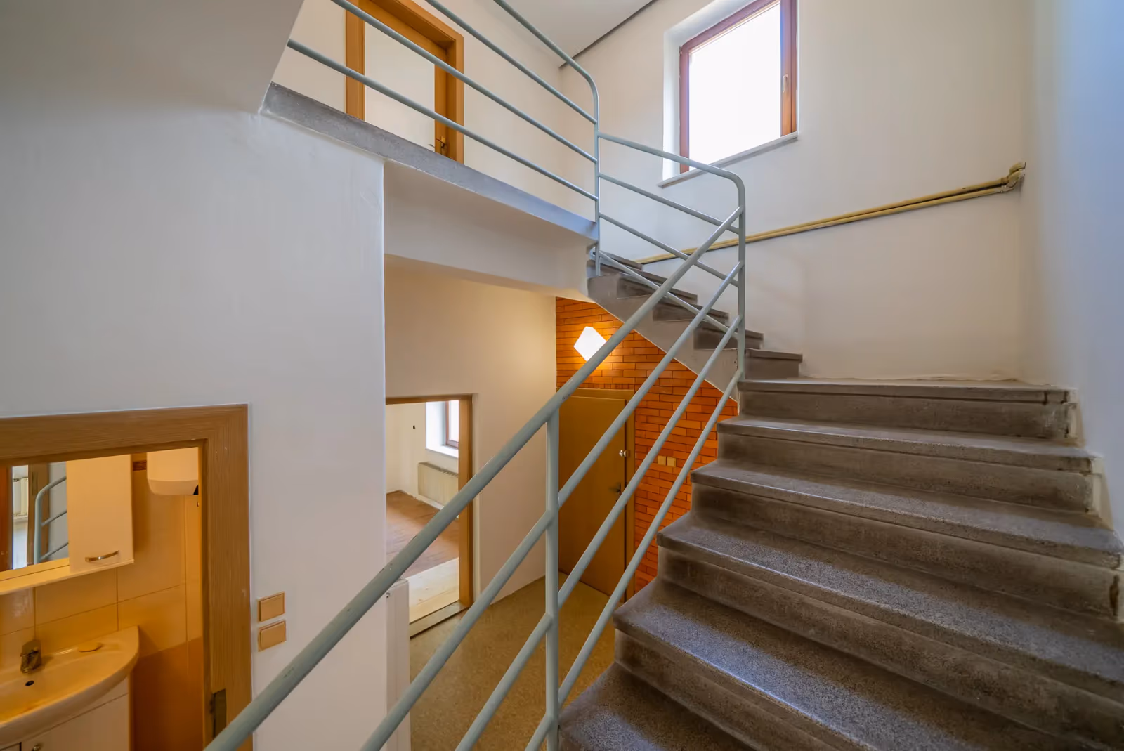 Schodiště do patra podél cihlové stěny, průhled do koupelny